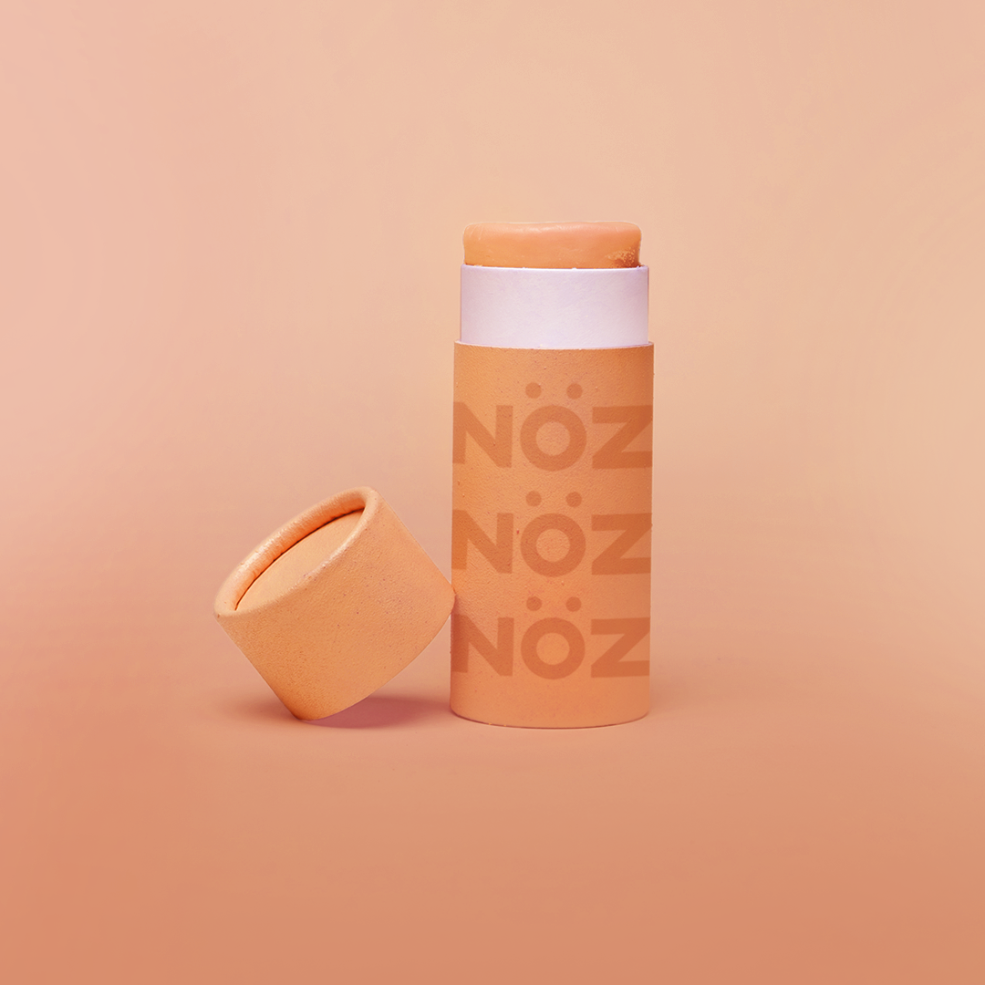 A single orange stick of Nöz sunscreen, the best reef safe, zinc oxide SPF for your face, with its cap off