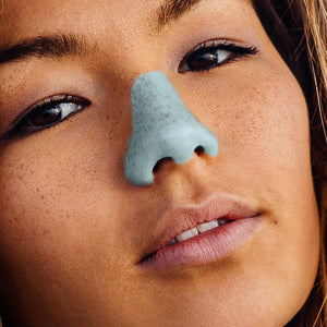 A close-up of a woman with freckles’ face with blue Nöz sunscreen, the best reef safe, zinc oxide SPF,  on her nose